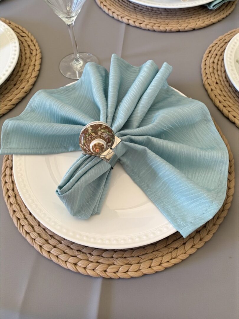 Elegant table setting with a light blue napkin and shell napkin ring.